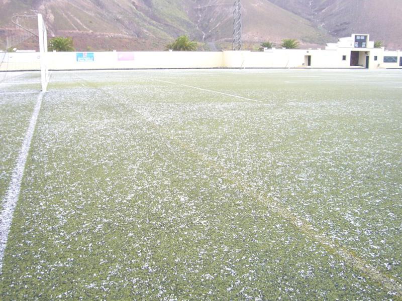 Inusual imagen del campo de fútbol en Yaiza, este lunes, con granizo sobre el césped.