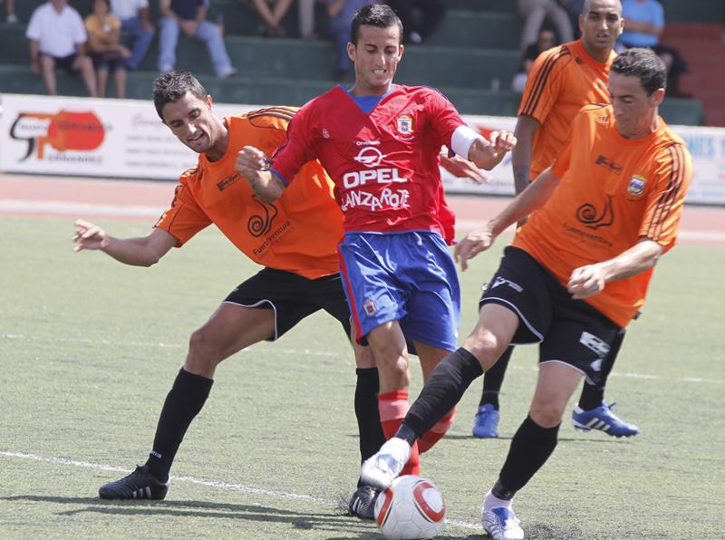 El jugador Rubén Rodríguez, disputando el balón entre dos rivales, cuando era capitán de la UD Lanzarote..